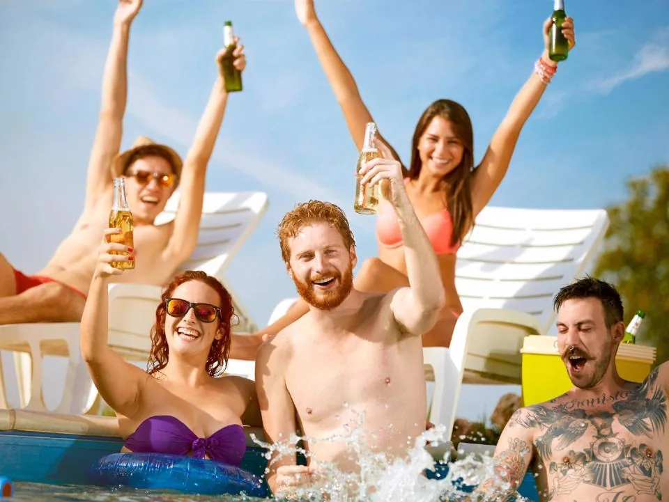 Friends celebrating with drinks in a swimming pool during a summer party